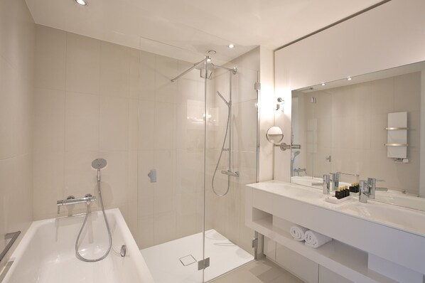 Un baño moderno con ducha de vidrio, una bañera blanca grande y un tocador con espejo.