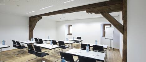 A conference room with tables, chairs, and a whiteboard.