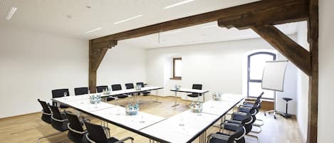 A conference room with a long table, black chairs, and a whiteboard.