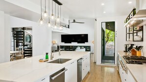 Een moderne keuken met een centraal kookeiland, inbouwapparatuur en een flatscreen televisie.