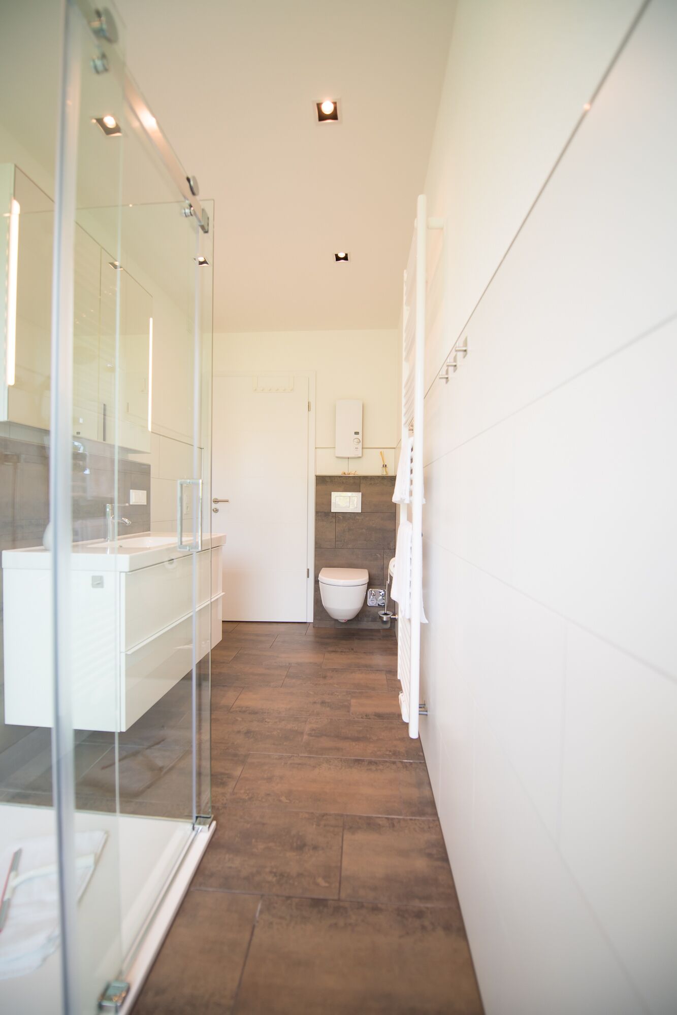 A modern bathroom with a glass shower enclosure, a white sink, and a toilet.