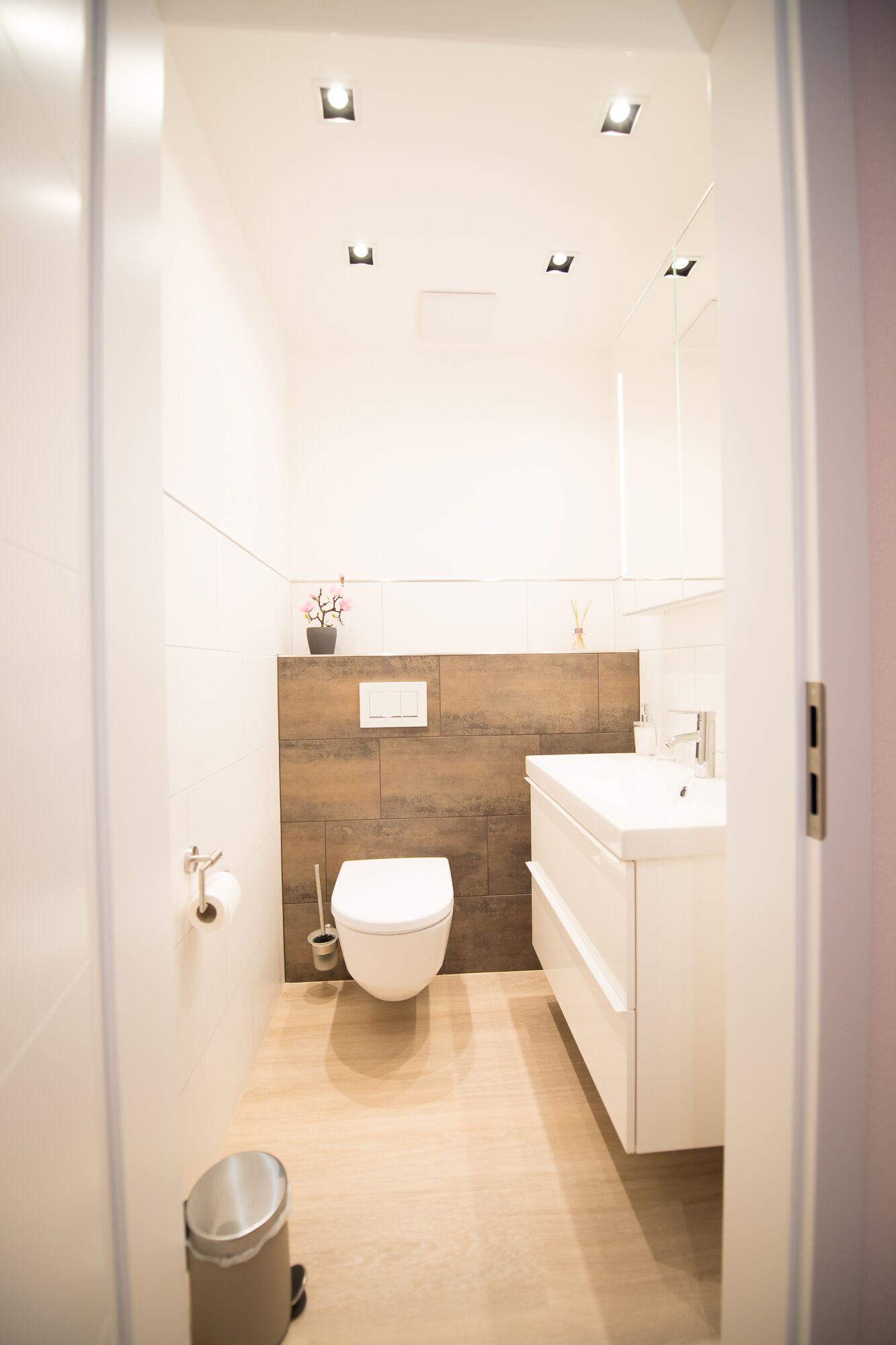 A modern bathroom with a white toilet, a sink, and a mirror.