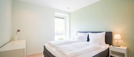 Un dormitorio moderno con una cama, mesitas de noche y una ventana.