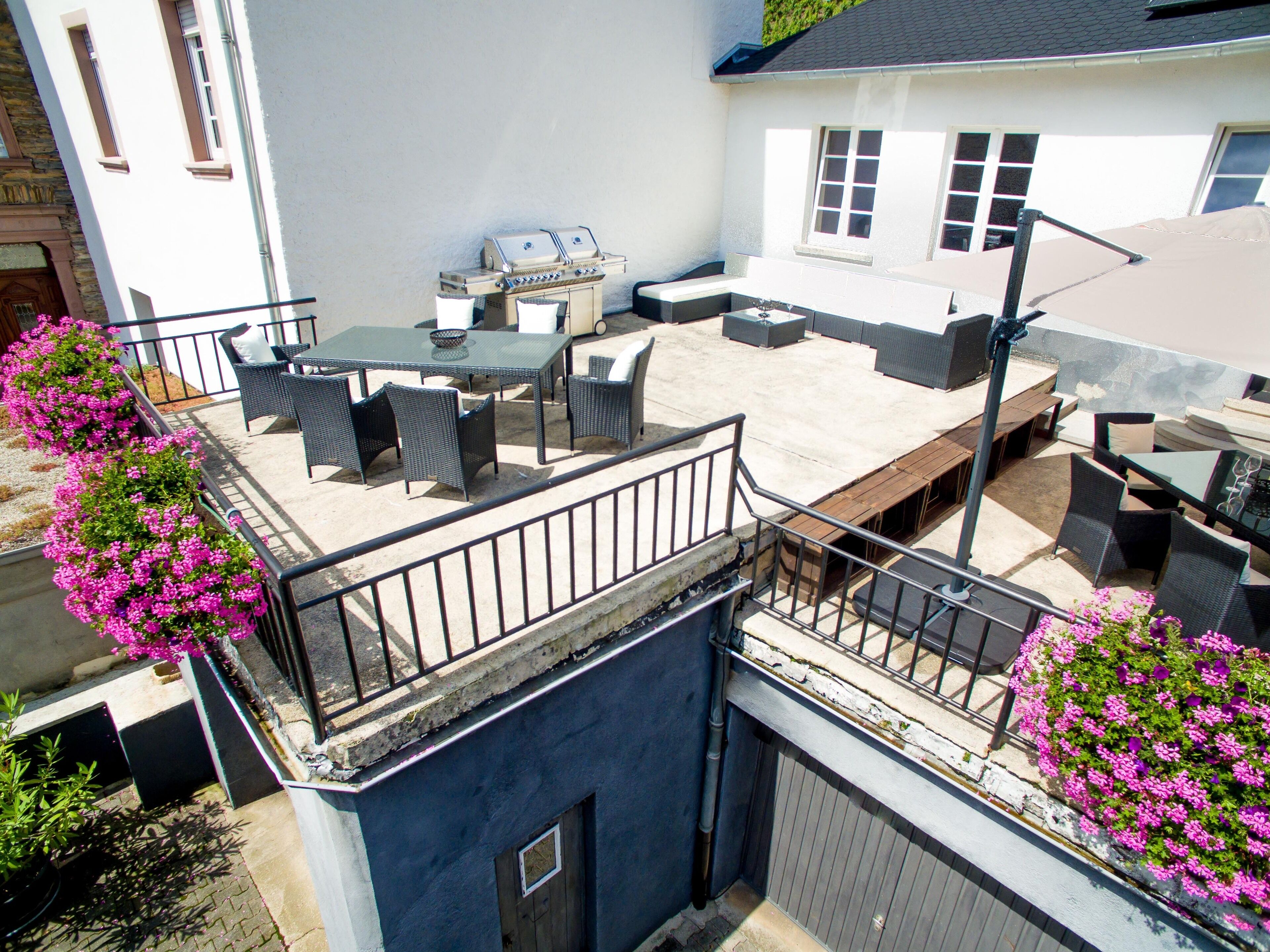 An outdoor patio with a barbecue grill, seating area, and flower boxes.