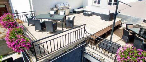 An outdoor patio with a barbecue grill, seating area, and flower boxes.