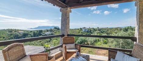 Un espacio de estar al aire libre con mobiliario de mimbre y vistas a un paisaje exuberante.