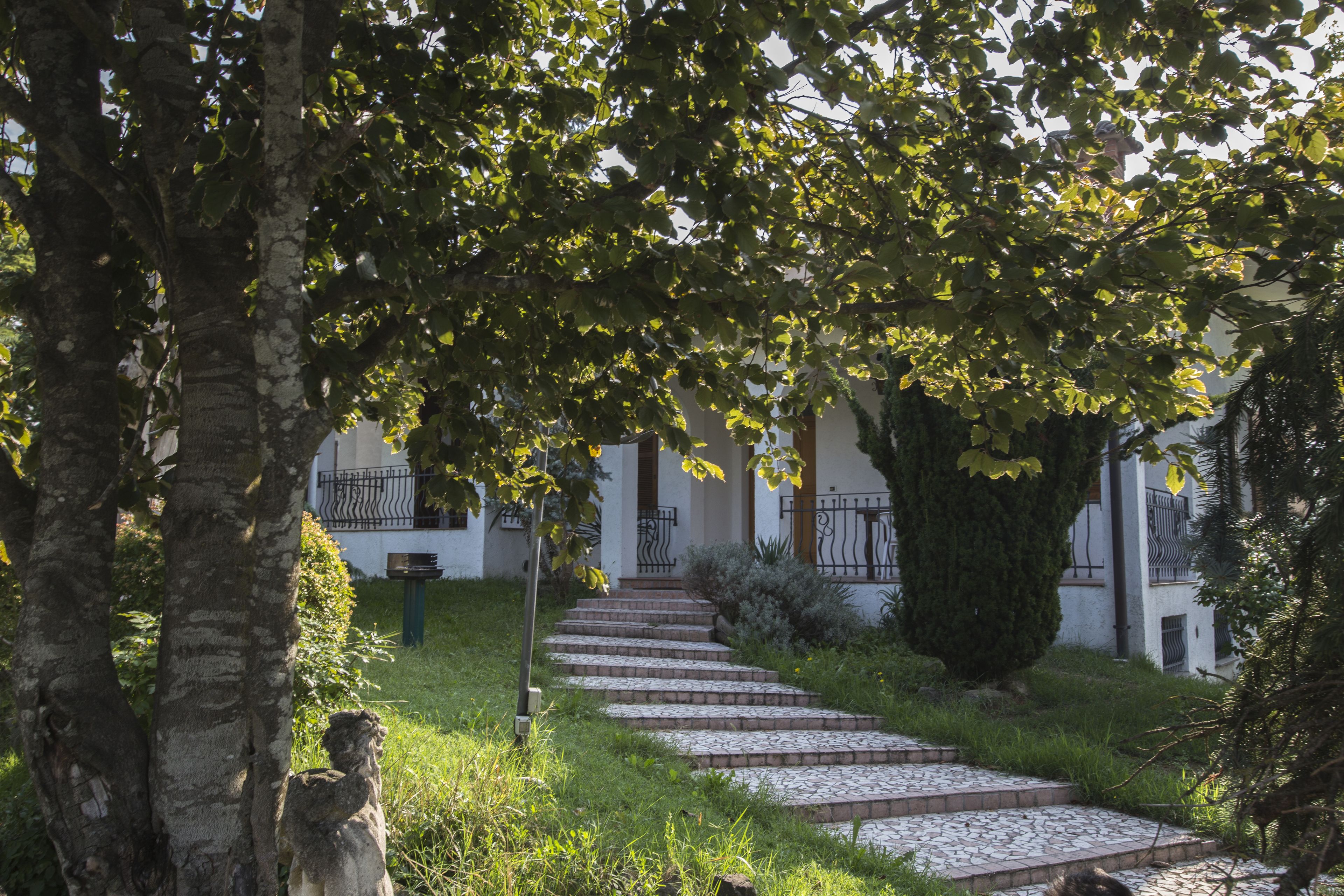 A stone pathway leading to a building with a white facade and black iron railings.