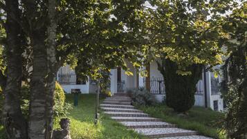 A stone pathway leading to a building with a white facade and black iron railings.