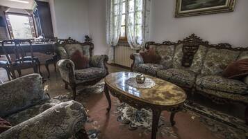 A traditional room with patterned sofas, a round coffee table, and a dining table with chairs.