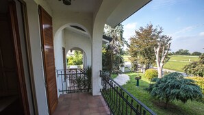 A balcony with a tiled floor, a wooden door, and a metal railing. - Villa Berra B&B Riva del Po (Berra)