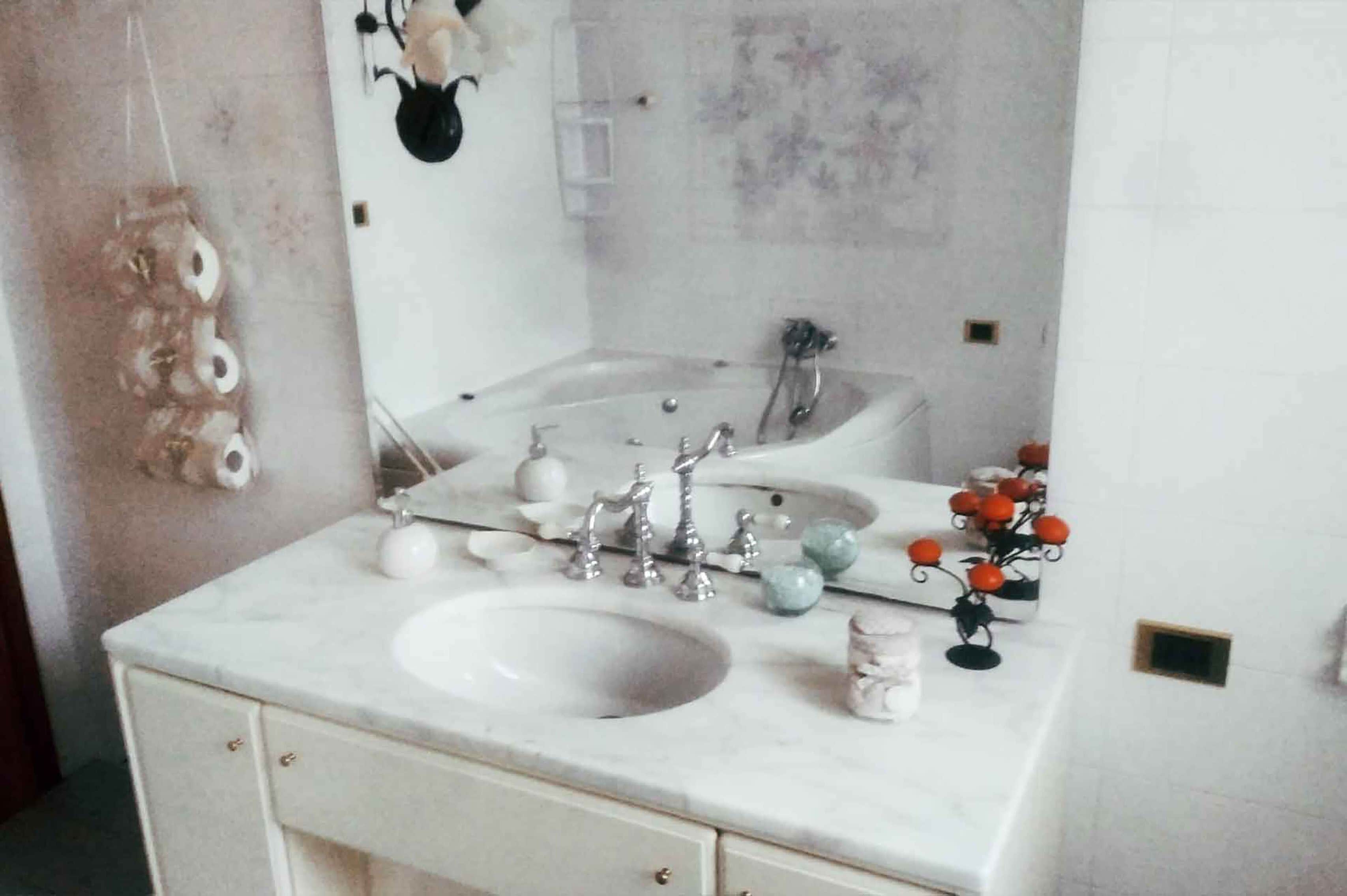 Un baño con lavamanos doble, un espejo y un jarrón decorativo.