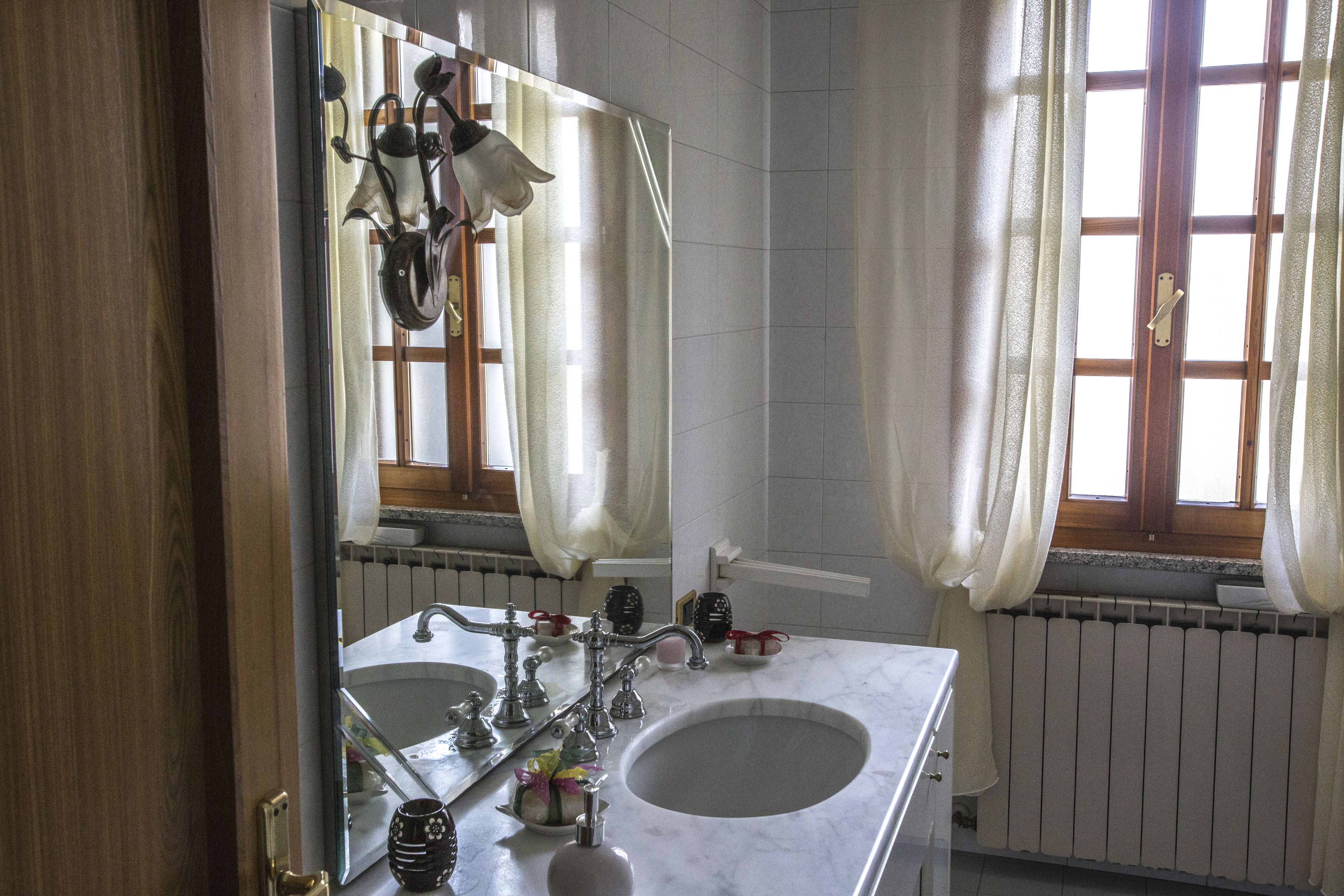 Un baño con dos lavamanos, un espejo y una ventana con cortinas.