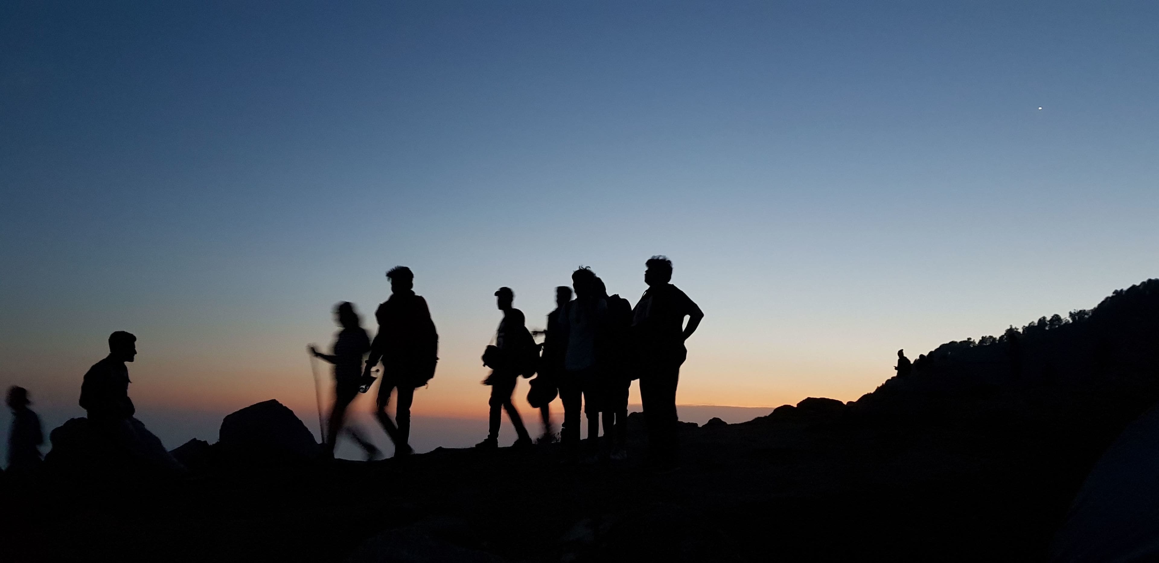 Silhouettes of people on a mountain at sunset.