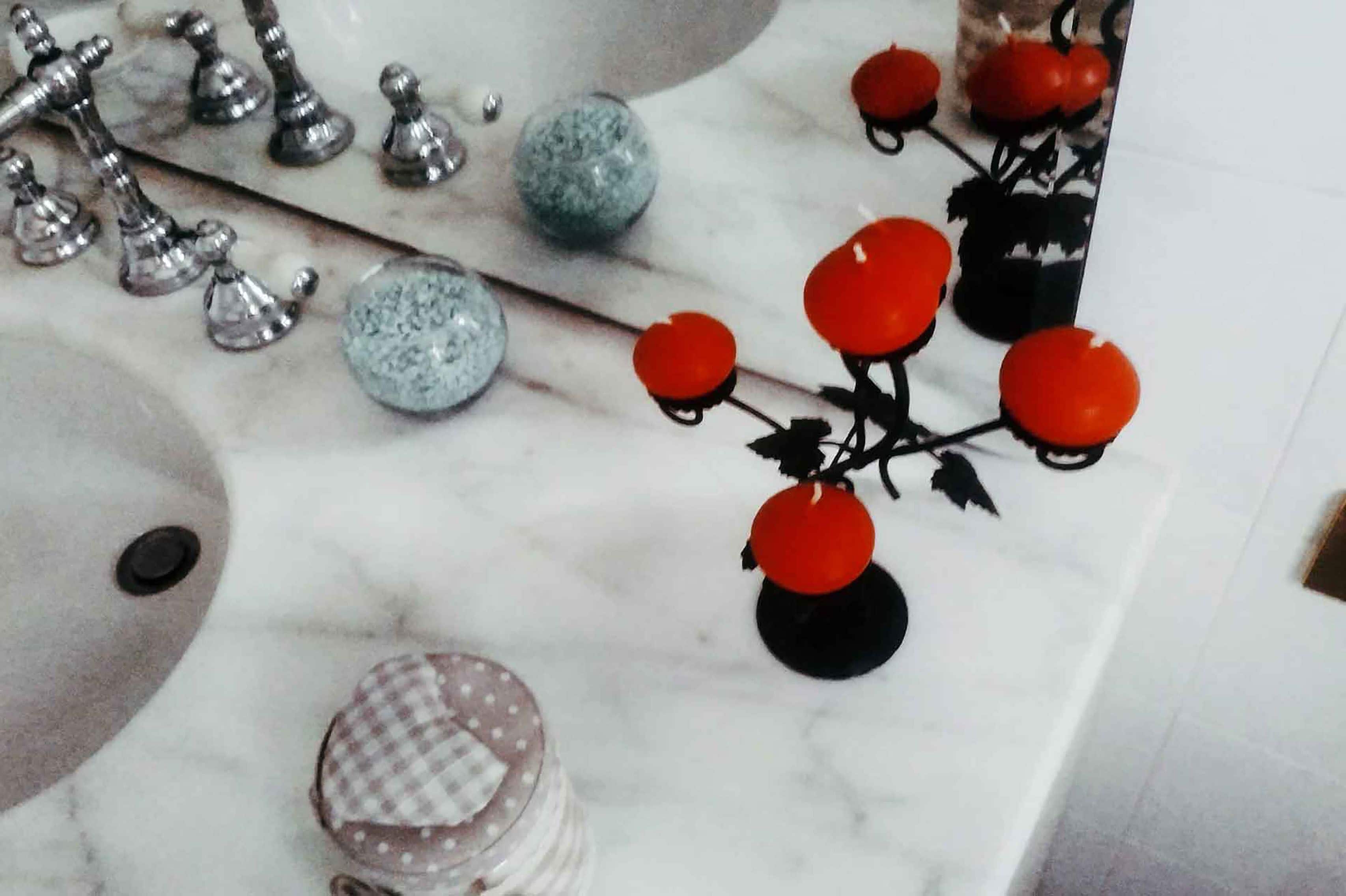 Una encimera de mármol con diversos utensilios de cocina, incluyendo una planta decorativa, una tapa cuadriculada y utensilios metálicos.