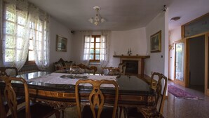 A dining room with a glass-top table, wooden chairs, and a chandelier. - Villa Berra B&B Riva del Po (Berra)