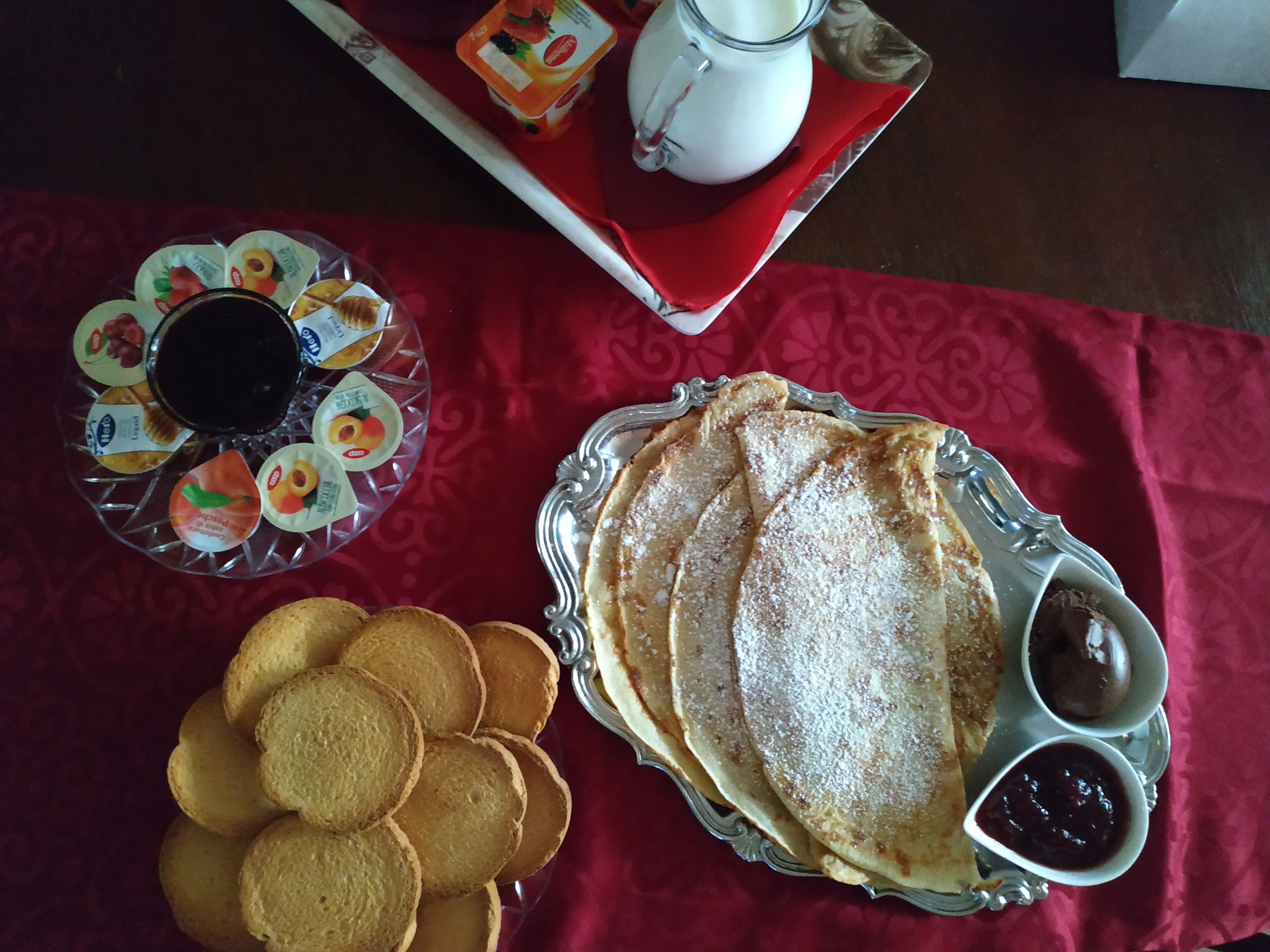 En frukostuppdukning med pannkakor, kakor och en tallrik med frukt.