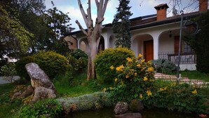 A serene garden with a pond, large rocks, and flowering bushes. - Villa Berra B&B Riva del Po (Berra)