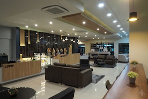 A modern interior with a reception desk, sofas, a dining table, and a kitchen area.