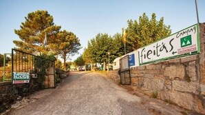 A stone pathway leading to a gated entrance with signs for 'fieitas' and 'Camping Bar Restaurante Bungalows'. - Camping Os Fieitás (O Grove)