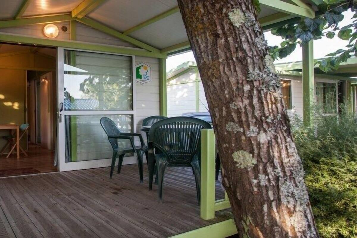 A covered outdoor area with a wooden deck, a table, and two chairs.