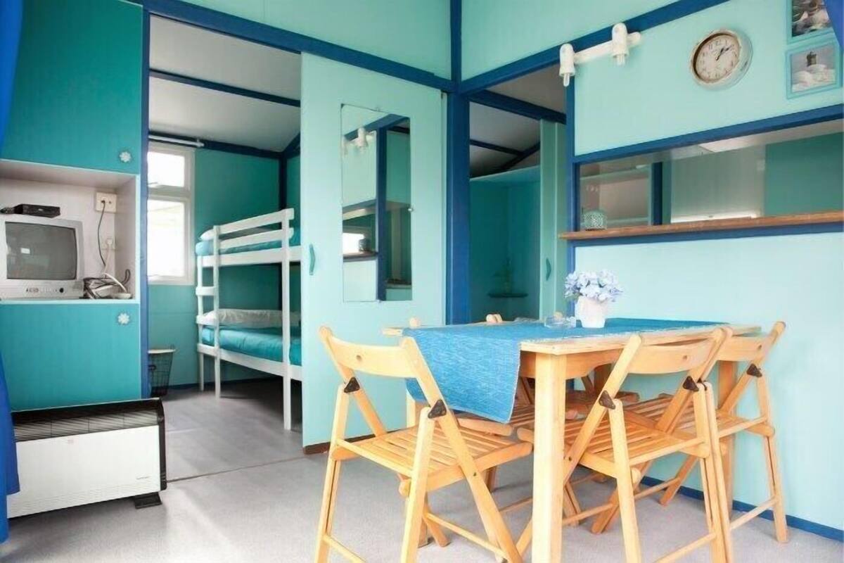 A room with bunk beds, a small table with chairs, a clock, and a television.