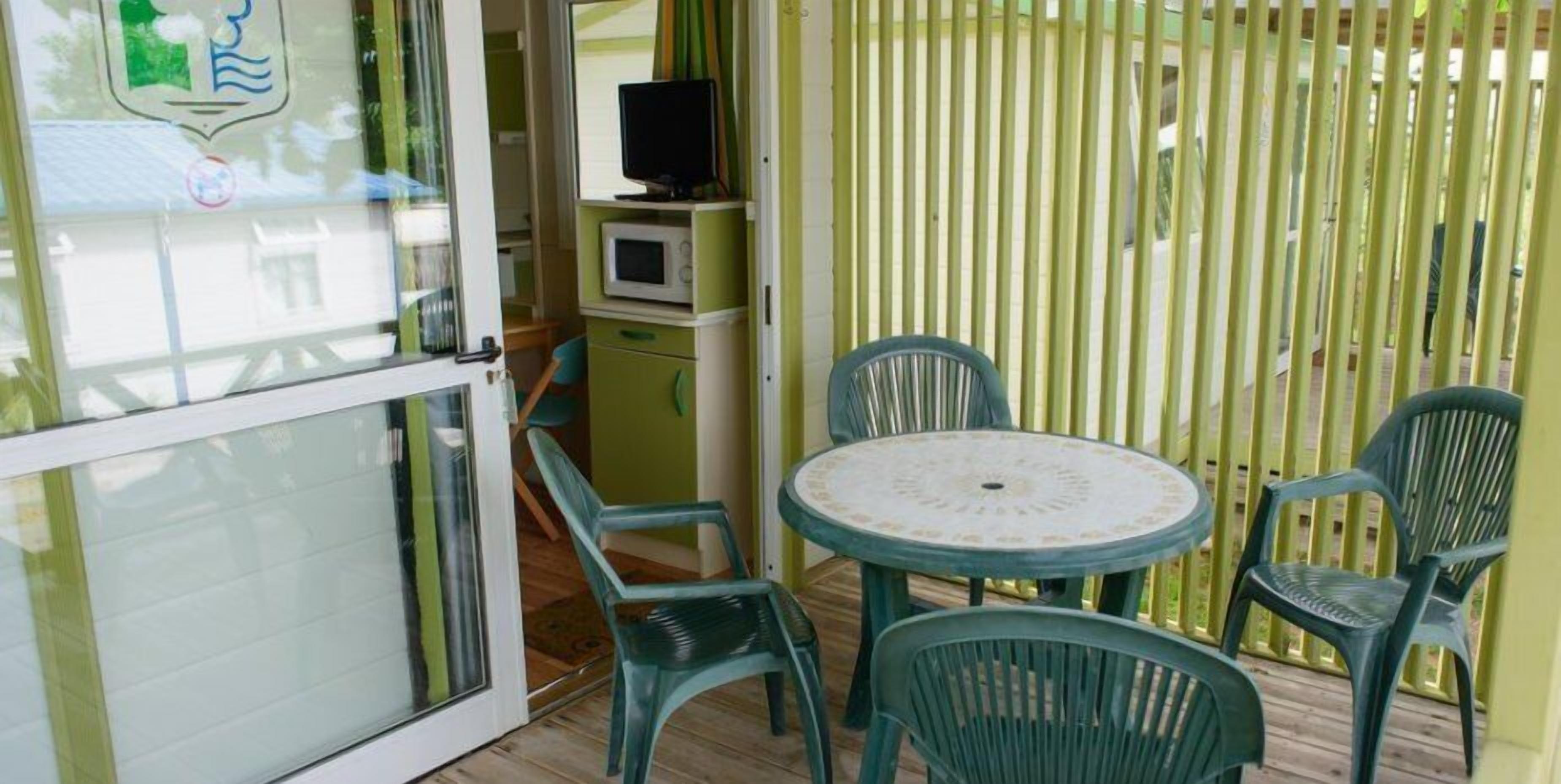 A small room with a glass door, a microwave, a television, and a round table with four chairs.