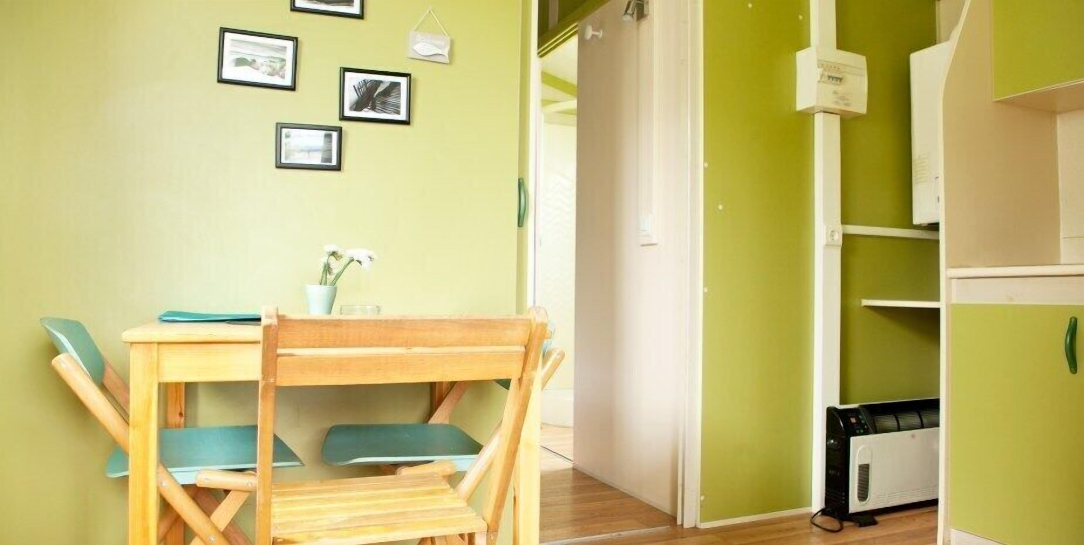 A room with a wooden table and chairs, a small potted plant, and a white radiator.