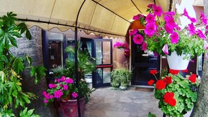 A covered outdoor area with potted plants and a stone pathway. - Hotel Jole (Andora)