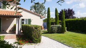 A house with a tiled roof, a front porch, and a gravel driveway. - Agriturismo Campallegro (Cecina)
