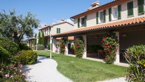 A building with a tiled roof, green shutters, and a covered porch with outdoor seating. - Agriturismo Campallegro (Cecina)