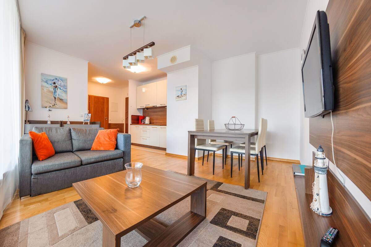 A modern living room with a sofa, coffee table, and dining area.