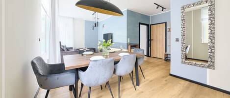 A modern dining area with a wooden table, grey upholstered chairs, and a pendant light.