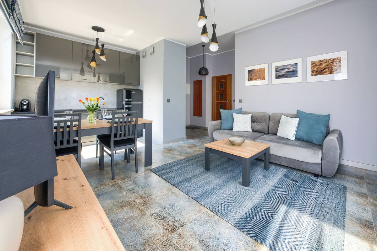 A modern living room with a sofa, coffee table, and dining area with chairs and a table.