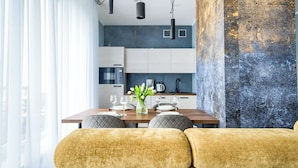 A modern dining area with a wooden table, cushioned chairs, and a vase of flowers. - Apartamenty Sun & Snow Aquamarina (Miedzyzdroje)