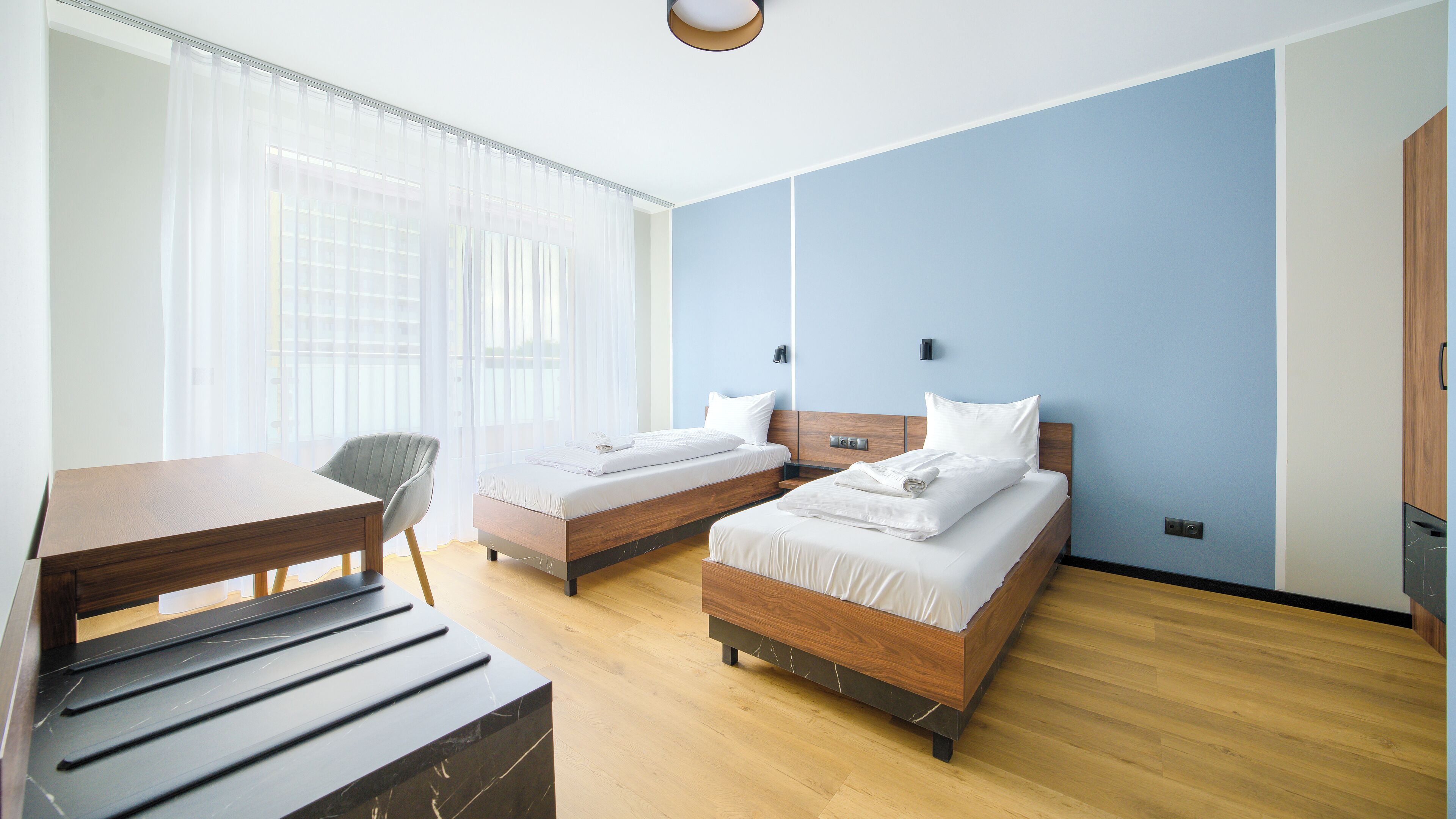 A hotel room with two beds, a desk, and a chair.