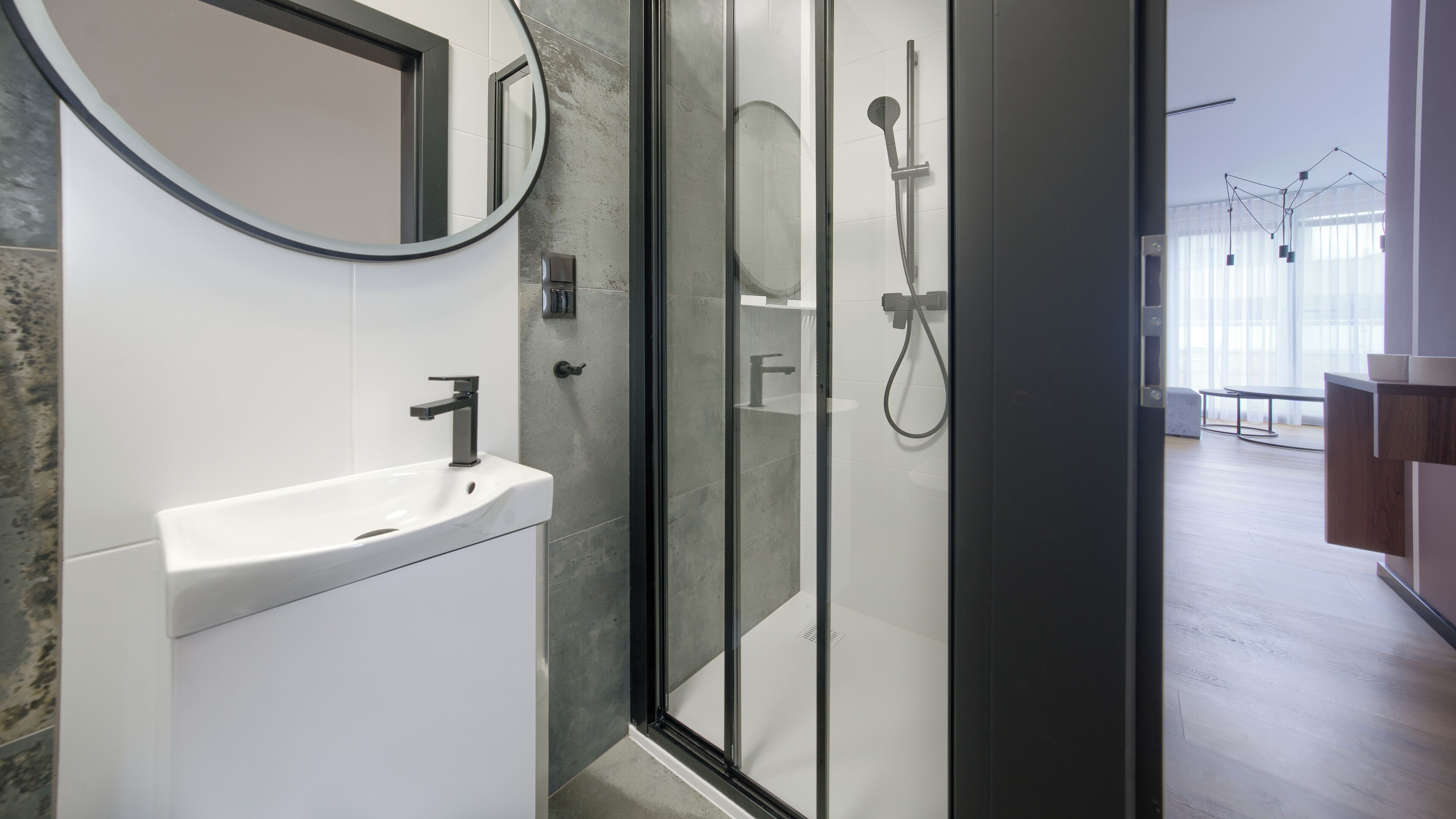 A modern bathroom with a white sink, a glass shower enclosure, and a large mirror.