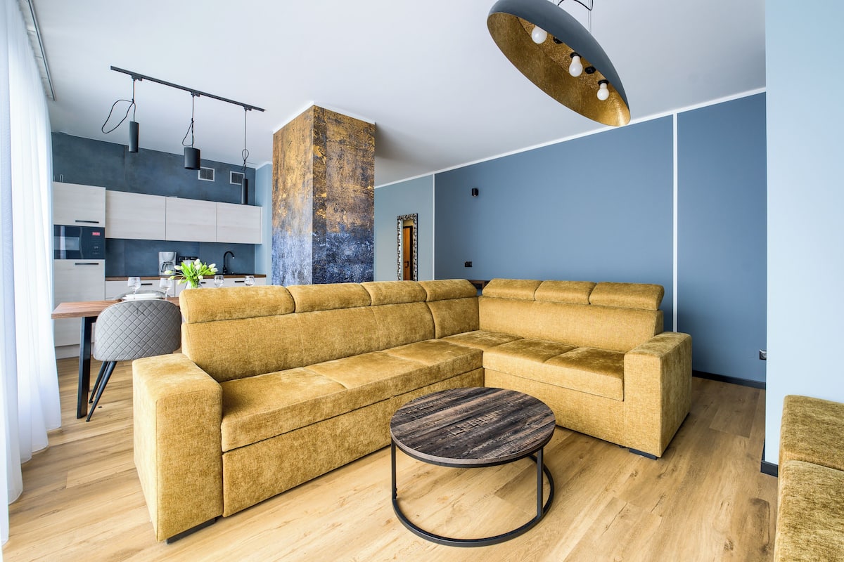 A modern living room with a sectional sofa, a round coffee table, and a kitchen in the background.