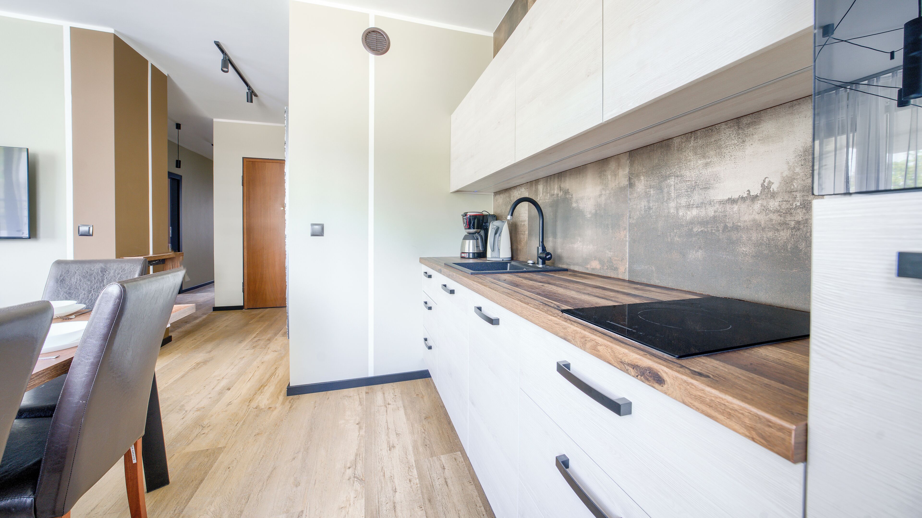 A modern kitchen with a wooden countertop, a built-in stove, and a coffee maker.