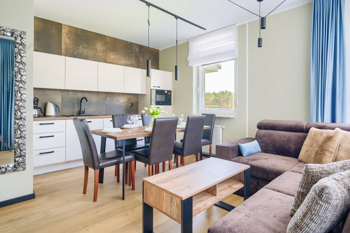 A modern living room with a sofa, coffee table, and dining area with chairs and a table.