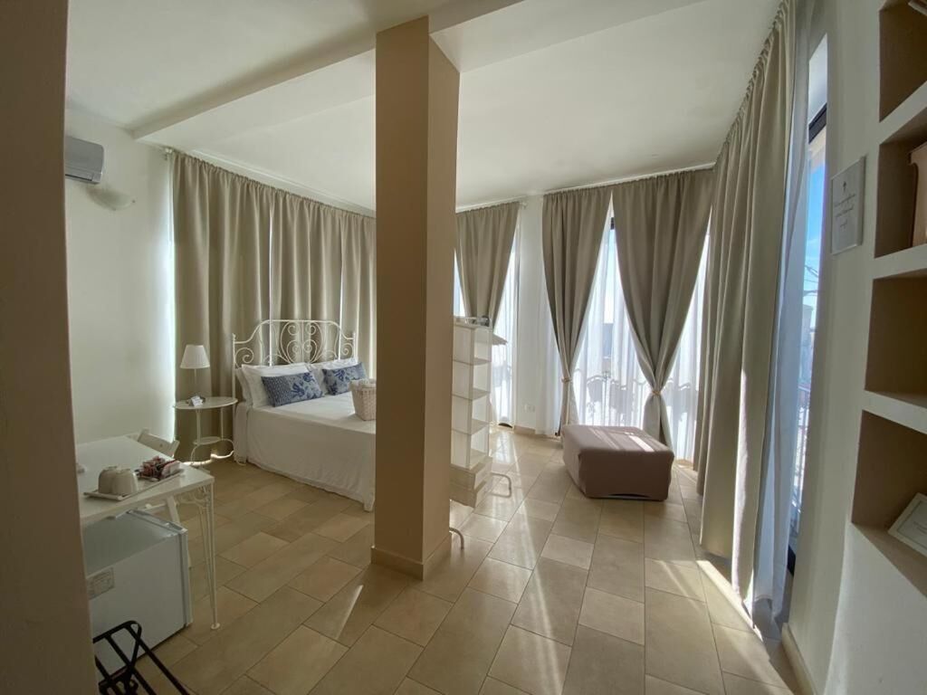 Ein Hotelzimmer mit Bett, Schreibtisch mit Lampe, Sessel, kleinem Tisch und Kleiderschrank.