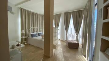 Ein Hotelzimmer mit Bett, Schreibtisch mit Lampe, Sessel, kleinem Tisch und Kleiderschrank.