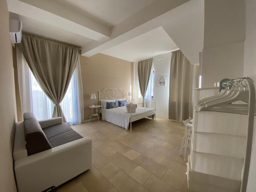 A hotel room with a sofa, a bed, a wardrobe, and a bathroom.