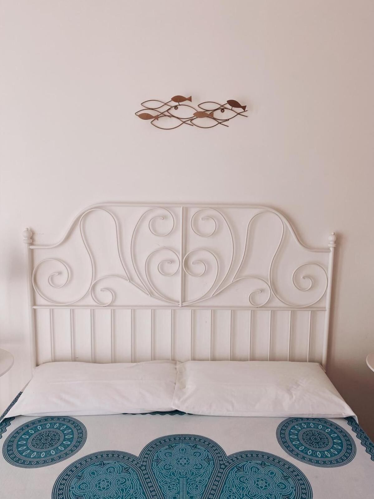 A bed with a white headboard and a decorative wall piece above it.