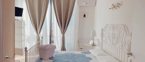 Une chambre à coucher avec un lit, une table de chevet, une lampe et une fenêtre avec des rideaux.