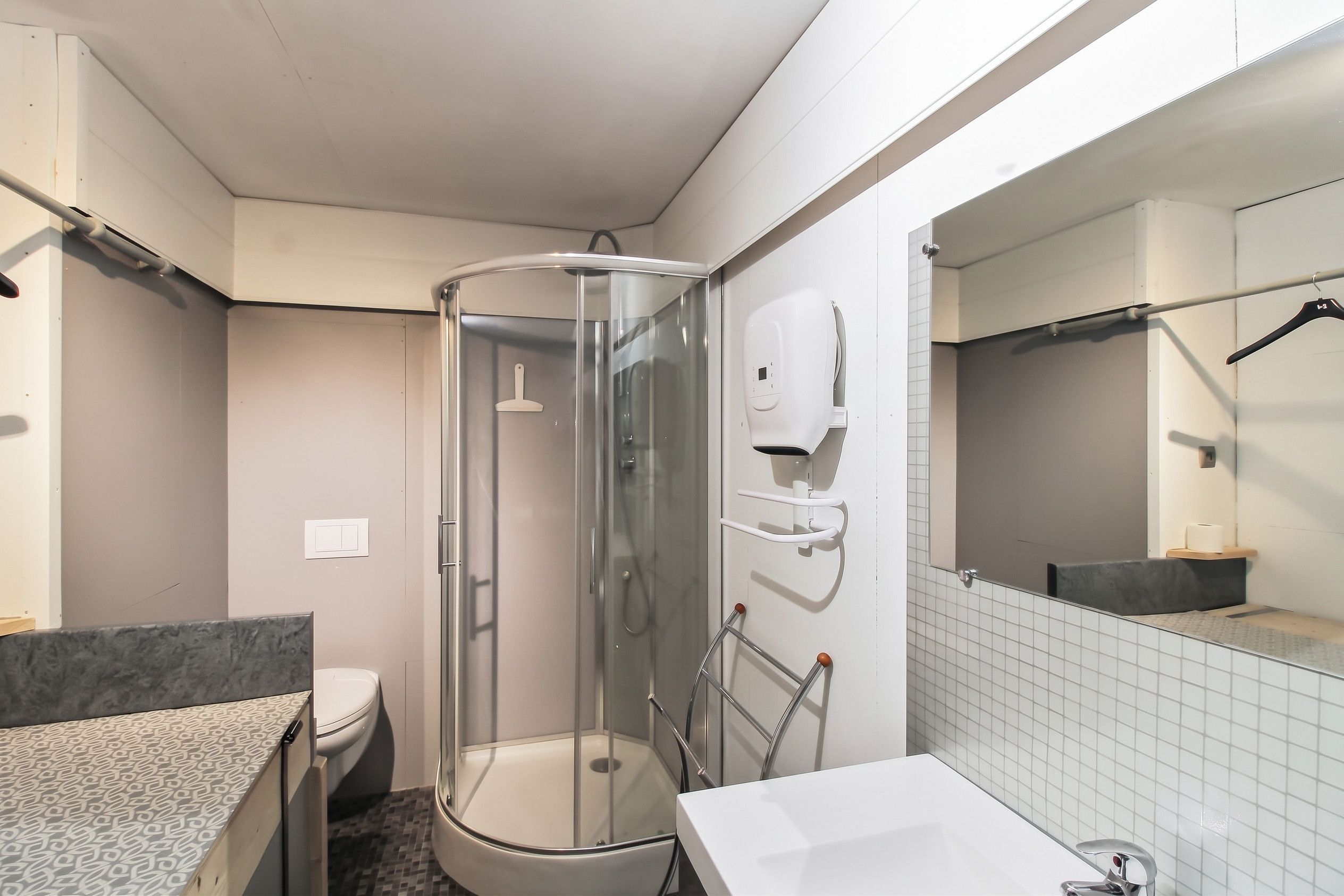 Une salle de bain moderne avec une douche à parois de verre, des toilettes, un lavabo et un miroir.