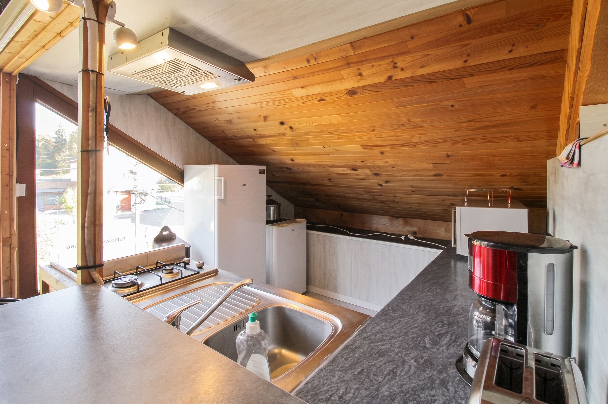 Cocina compacta con estufa a gas, un lavamanos, refrigerador y horno de superficie.