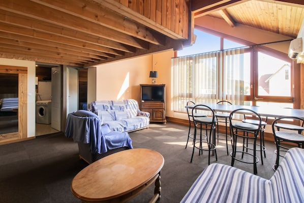 Una habitación con techo de madera, un sofá, una mesa y un televisor.