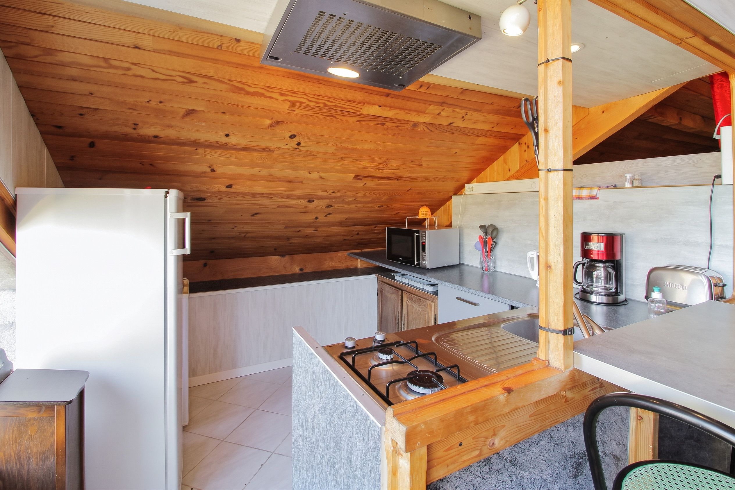 Une cuisine de taille réduite équipée d’une cuisinière à gaz, d’un four à micro-ondes et d’un grille-pain.