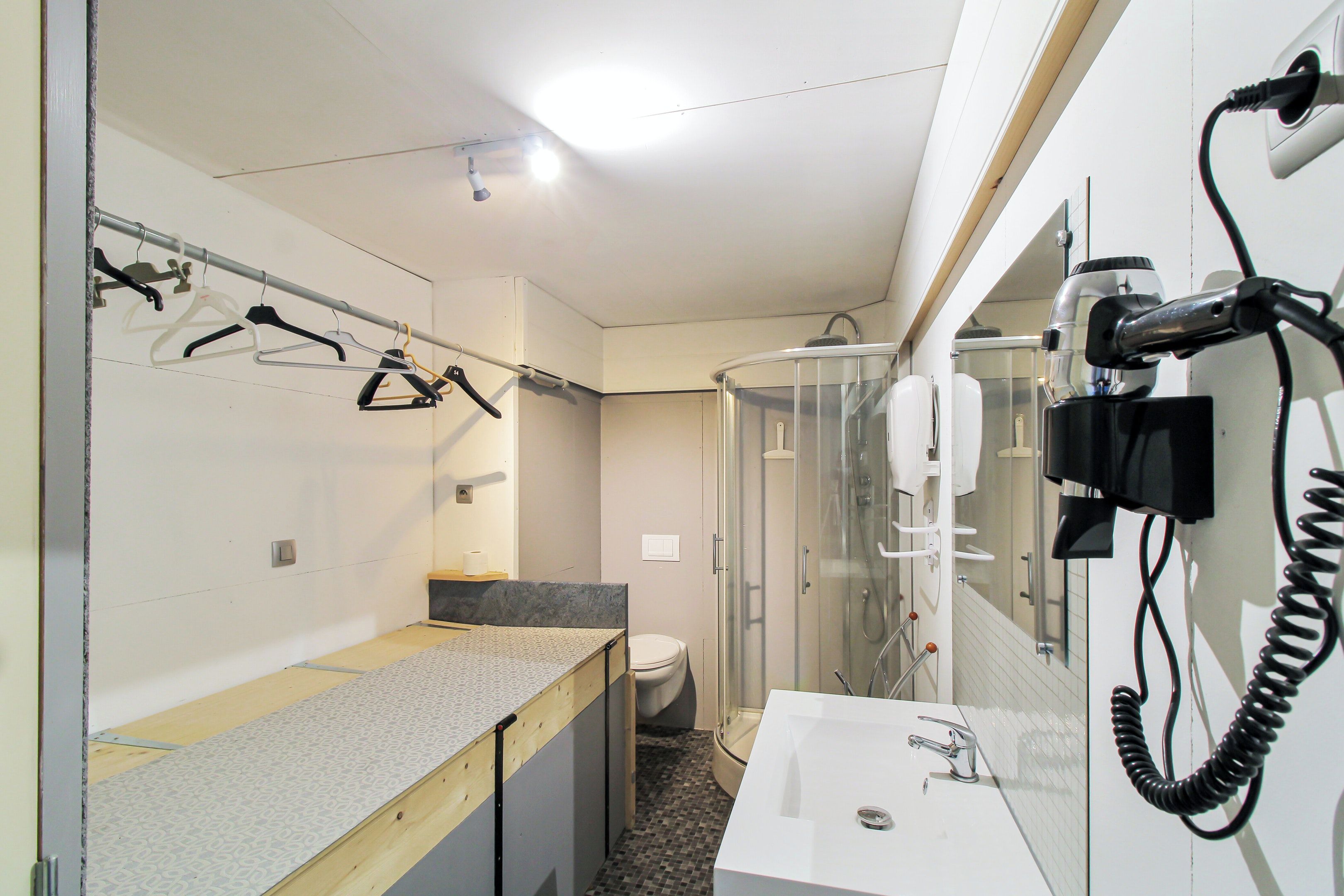 A compact bathroom with a shower, toilet, and a sink with a mirror.