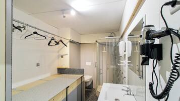 A compact bathroom with a shower, toilet, and a sink with a mirror.
